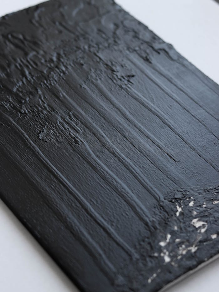 Close-up of textured black acrylic paint on canvas showcasing artistic abstract design.