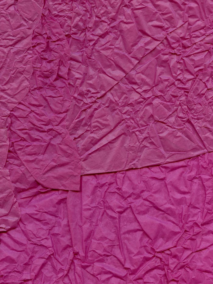 Crumpled pink paper texture in a vibrant abstract design, perfect for creative projects.