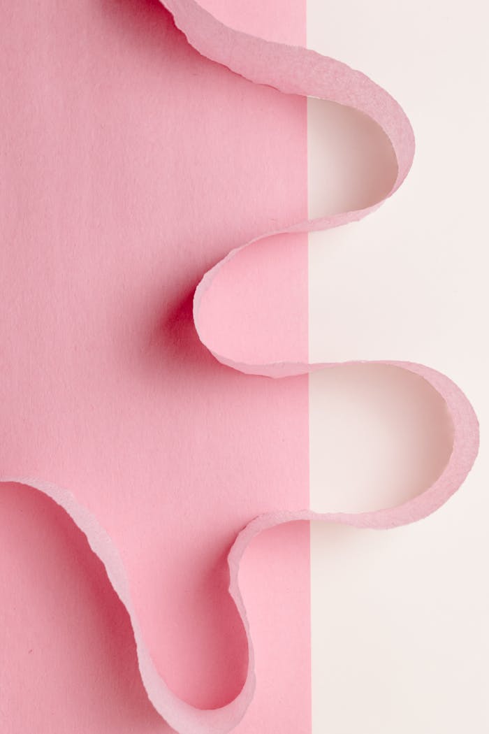 Artistic composition featuring torn pink paper against a white background in a vertical layout.